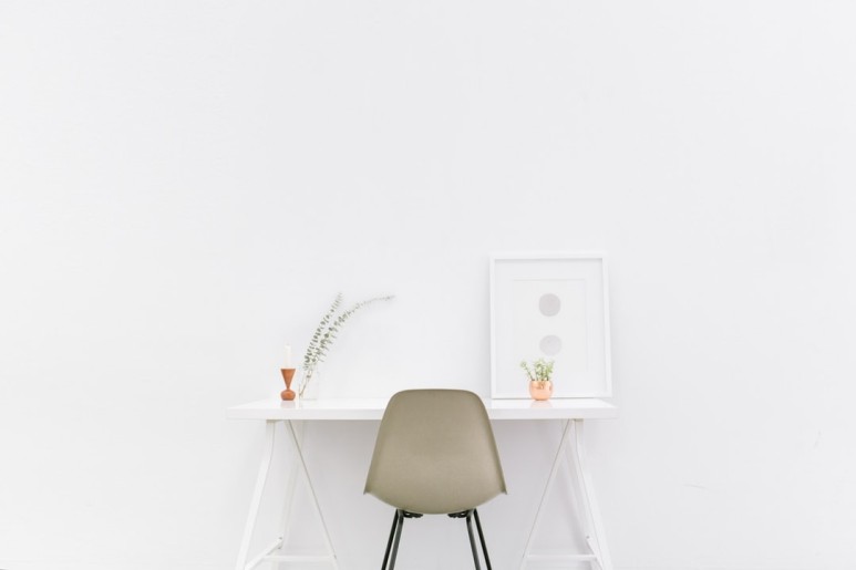 하얀 방의 한 가운데에 책상과 의자가 놓여있는 사진